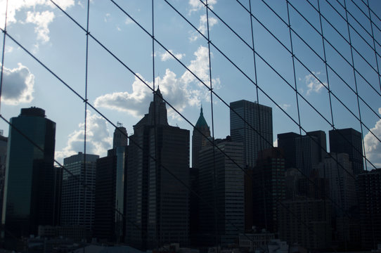Fototapeta A cluster of buildings situated in New York City's lower Manhattan as seen through the high-tension wires of the iconic Brooklyn Bridge.