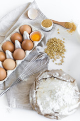 Fototapeta na wymiar Ingredients for homemade baking. Eggs, milk, flour, sugar. White background, side view