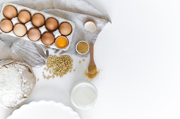 Ingredients for homemade baking. Eggs, milk, flour, sugar. White background, top view, space for text