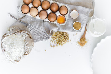 Ingredients for homemade baking. Eggs, milk, flour, sugar. White background, top view, space for text