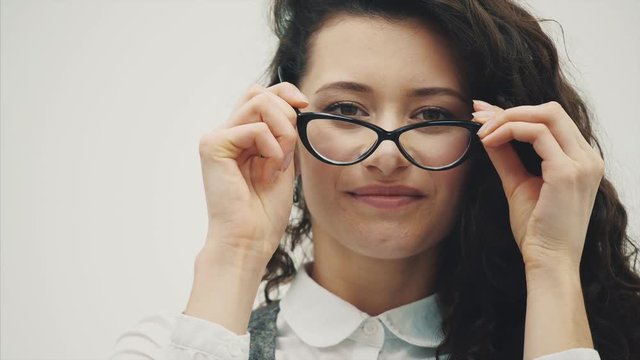 Portrait of a beautiful young brunette. A light-skinned girl with shaggy hairstyles smiling.Dressing up the glasses is just watching.
