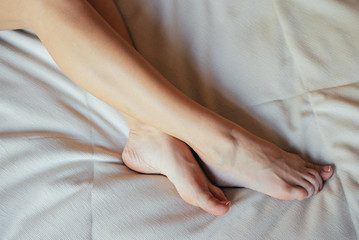 Young girl resting on bed, girl's legs lie on bed