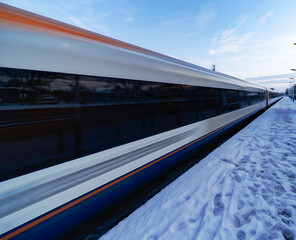 Fototapeta premium Train departing a UK station at speed in the snow