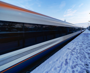 Train departing a UK station at speed in the snow