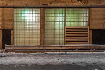 Side view of vintage building with glowing square windows in alleyway