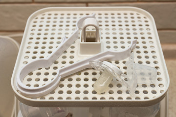 The bottle tongs, used to removing feeding bottles, soother, bottle nipples and other accessories from sterilizer unit. Close-up of baby bottle sterilizer