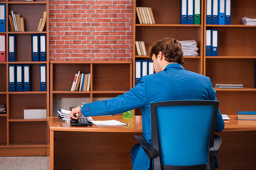 Young handsome employee sitting in the office  