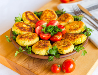 Homemade ruddy cheese and potato cutlets, decorated with fresh tomatoes and parsley, in ceramic plate on wooden board © v_tynka