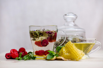 herbal tea with a slice of lemon and fresh fruit in a clear glass mug. honey in honeycombs.