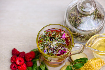herbal tea with a slice of lemon and fresh fruit in a clear glass mug. honey in honeycombs.