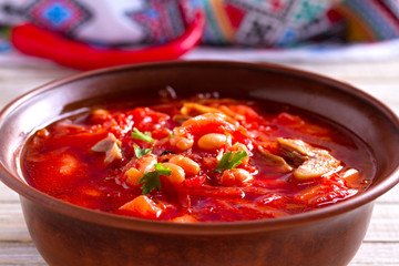 Soup borscht made with vegetables, meat, beans and beet root in bowl on wooden table