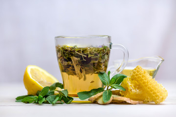 herbal tea with a slice of lemon and fresh fruit in a clear glass mug. honey in honeycombs.