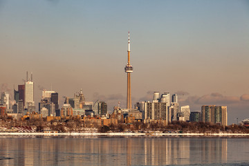 Obraz premium Toronto, CANADA - February 1th, 2019: Panoramic Canadian winter landscape near Toronto, beautiful frozen Ontario lake at sunset. Scenery with winter trees, water and blue sky.