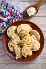 Dumplings, filled with potato. Dumplings with filling and sour cream in wooden spoon. overhead, vertical