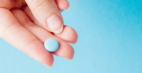 Close-up shot of blue pill in nurse's hand isolated over blue background