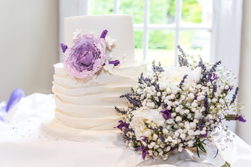 White wedding cake covered in white icing and a floral decoration