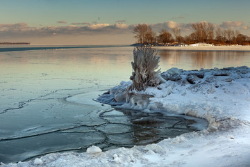 Toronto, CANADA - February 1th, 2019: Panoramic Canadian winter landscape near Toronto, beautiful frozen Ontario lake at sunset. Scenery with winter trees, water and blue sky.