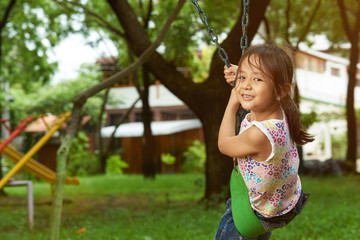 Asian girl on a swing looking at the camera