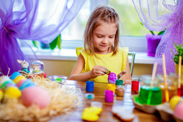 colorful painted eggs, flowers in vase. Happy easter girl having fun and painting eggs. small child at home. spring holiday