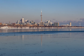 Naklejka premium Toronto, CANADA - February 1th, 2019: Panoramic Canadian winter landscape near Toronto, beautiful frozen Ontario lake at sunset. Scenery with winter trees, water and blue sky.