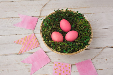 Easter. Easter eggs lie in a basket, a nest with moss on a white wooden background. Spring, April. selective focus