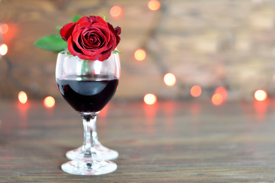 Valentines red wine and rose on wooden background with copy space. Love concept.