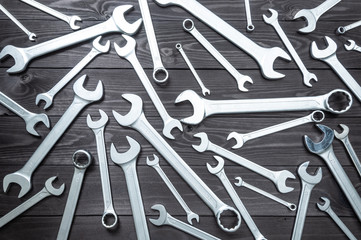 set of chromed wrenches on a dark wooden workbench. top view