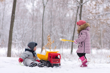 two little kids are playing at the snowtime