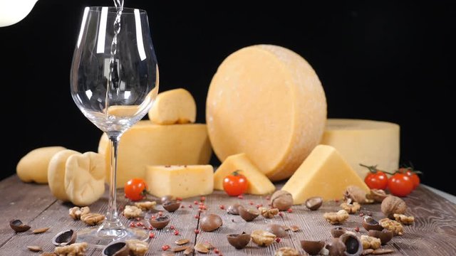White wine is poured into a glass with a varieyty of hard cheese on background. Food art concept. Restaurant serving. Catering concept. Holidays festive concept. hd