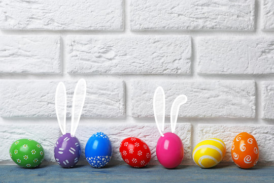 Decorated Easter eggs on table near brick wall. Space for text