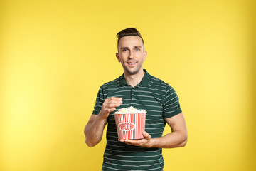 Man with popcorn during cinema show on color background