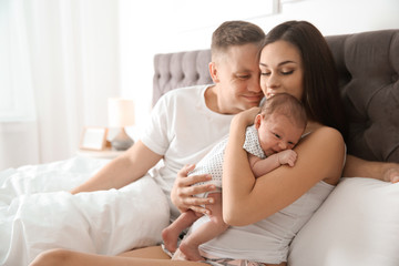 Fototapeta na wymiar Happy couple with their newborn baby on bed