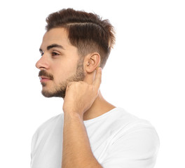 Obraz premium Young man adjusting hearing aid on white background