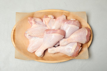 Plate with raw chicken wings and drumsticks on gray background, top view. Fresh meat