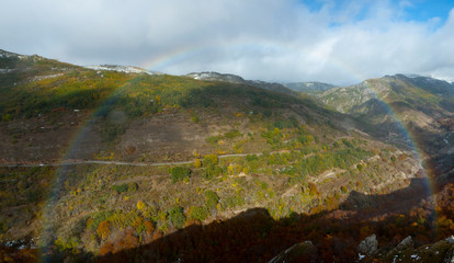 Whole rainbow in a mountainous landscape with beech forests.