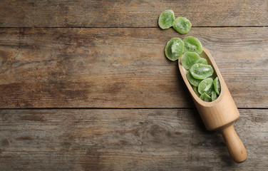 Scoop of dried kiwi on wooden background, top view with space for text. Tasty and healthy fruit