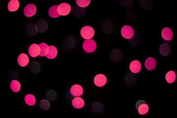 Abstract magenta bokeh texture on black background. Defocused sparkles.