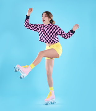 Young woman with retro roller skates on color background