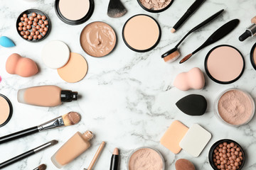 Flat lay composition with skin foundation, powder and beauty accessories on marble background. Space for text