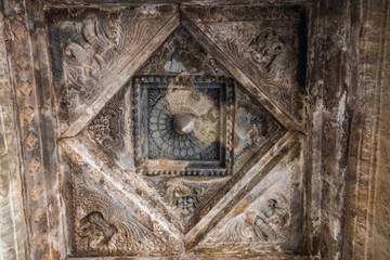 Belavadi, Karnataka, India - November 2, 2013: Veera Narayana Temple. Gray stone Sculpture set in square mandala on ceiling of Mandapam shows some monster faces and a lotus shape.