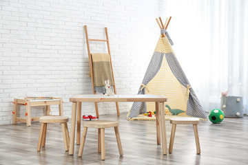 Cozy kids room interior with table, stools and play tent