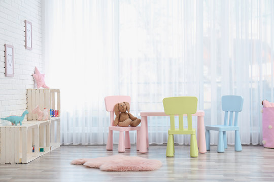 Cozy kids room interior with table, chairs and toys