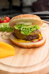 Homemade hamburger with fresh vegetables served on a wooden tray. Homemade preparing concept.