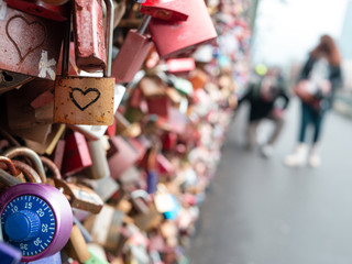 Love locks at Hohenzollern bridge in Cologne, Germany, with couple defocused in background - 247084330