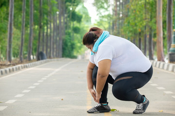 Fat woman tying her shoelaces before jogging - obrazy, fototapety, plakaty