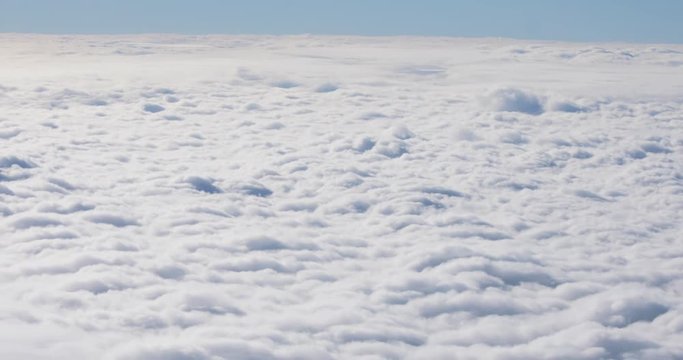 Stunning view of the thick cloud cover under the beautiful blue sky on sunny morning. Flying over the fluffy clouds.