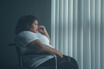 Overweight woman looks sad in the wheelchair - Powered by Adobe