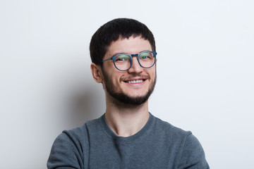 Fototapeta premium Portrait of smiling young man with glasses over white studio background