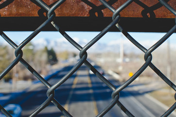 A view through the chain linked fence above the city street in the winter sun. 
