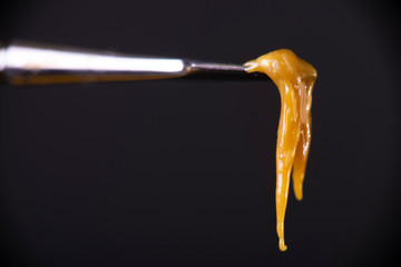 Detail of dab tool with cannabis concentrate aka rosin isolated over black